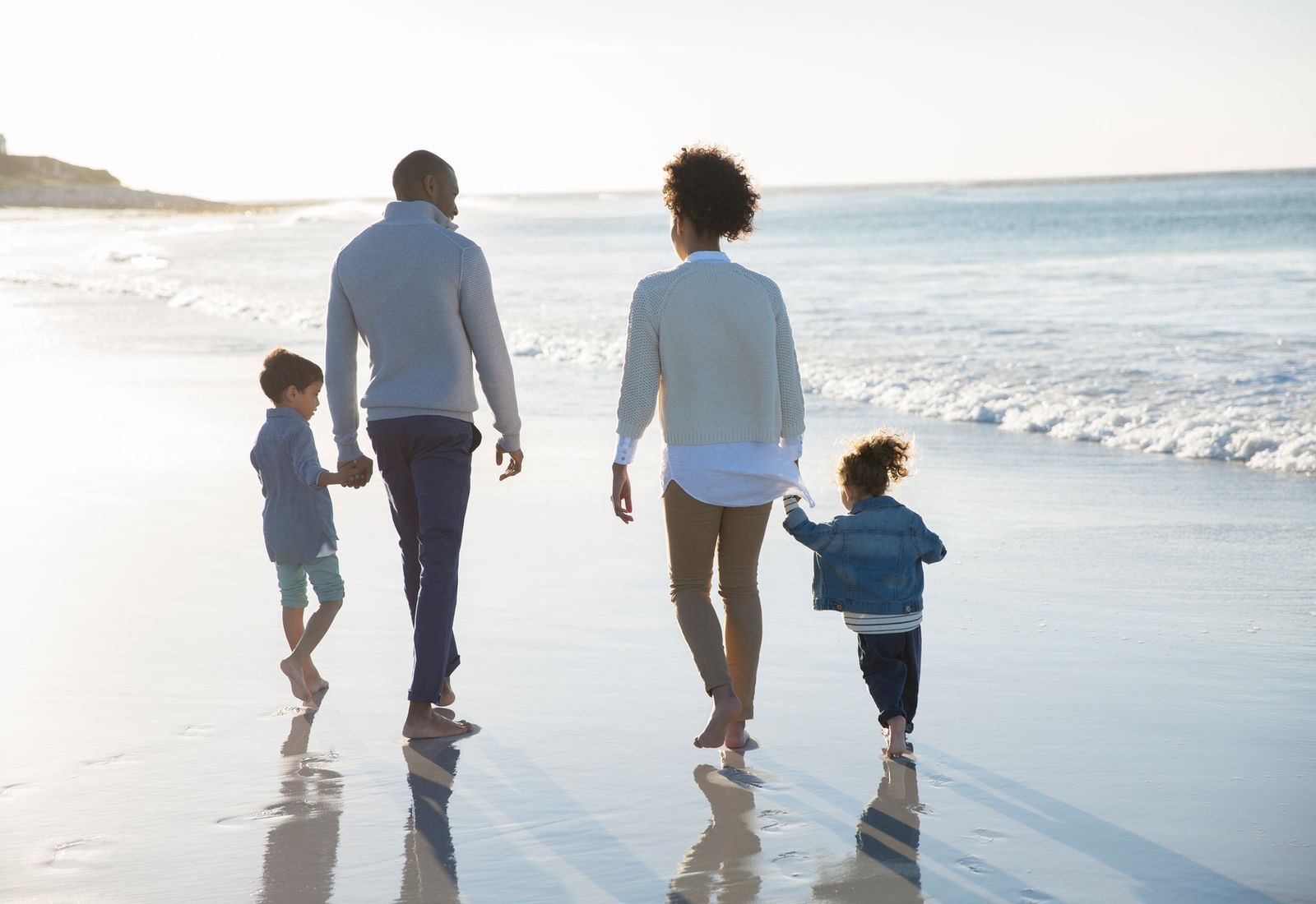 A family walking together along the beach at sunset